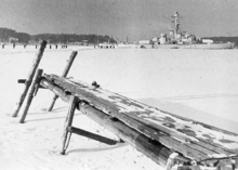 Frozen sea with a dock in front and a ship in behind.