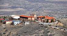 A cluster of building with orange slate roofs, seen from a hill above