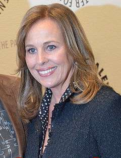 A women with brunette hair, wearing blue sweater with white pokadots.