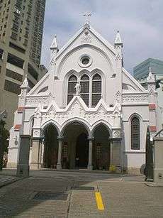 The facade of a gothic revival cathedral with flanking flying buttress on both sides