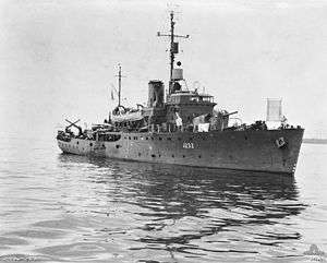 A World War II-era corvette at sea. The ship is not moving and the ocean is flat.