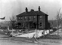 Two-storey brick house with bay window and two large chimneys.