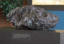 A piece of a gray meteorite on a pedestal