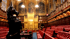 Wood panelled room with high ceiling containing comfortable red padded benches and large gold throne.