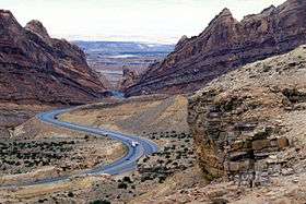 A highway snaking through a sandstone canyon that progressively narrows around the highway corridor