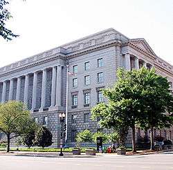 Exterior view of a large building, partly obscured by trees