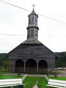 Wooden church with a single central tower covered in shingles.