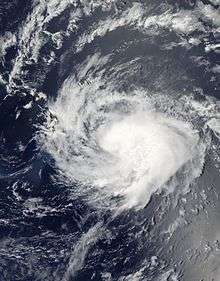 Satellite image of a tropical cyclone to the left of small landmasses.