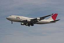 A Boeing 747–400 aircraft in mid air, with greyish blue sky in the background