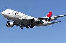 A Boeing 747–400 aircraft in mid air, with blue sky in the background