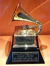 A gold gramophone trophy with a plaque set on a table