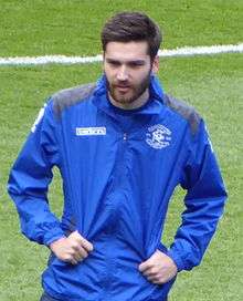 White man with dark hair and beard wearing sports kit