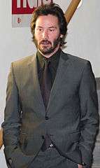 A candid portrait of Keanu Reeves wearing a gray suit.