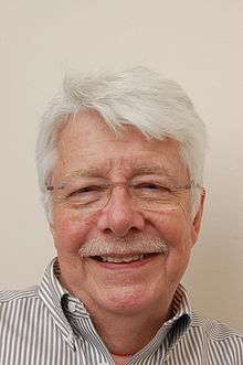 A white-haired man with moustache and glasses