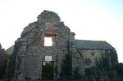 Stone wall with window of ruined building.