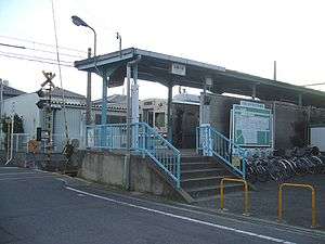 Entrance to Koginosato station. A train can be seen waiting at the platform.