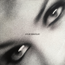 A black-and-white, and motion-blurred image of a woman's (Kylie Minogue) eyes. The song title and woman's name is superimposed on the image.