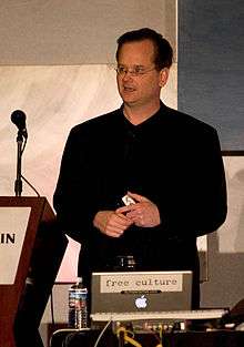 Lawrence Lessig standing at a podium with a microphone, with a laptop computer in front of him.