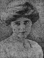 A grainy newspaper photo of a woman in her early 20s who looks straight at the camera. Her hair is coiffed, and she is wearing a white blouse