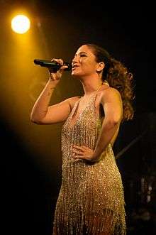 A woman in a beaded dress holding a microphone.