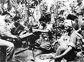 Group of cadets being trained by a Marine on usage of a water-cooled machine gun.