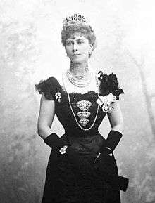 Thin Mary wearing a formal dress, a rope of pearls and a tiara