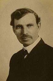 A black and white picture of a man in a suit with a large mustache