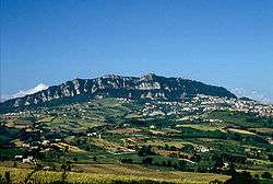 Mountain with some rocks and three fortresses on top.