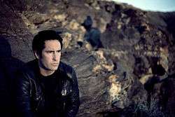 A man sitting in front of a field of craggy rocks.