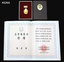 A photograph of the Prize awarded to Moon Sun Myung in 2012. It shows a gold medal depicting the Korean peninsula, and a certificate with calligraphic writing and a seal.