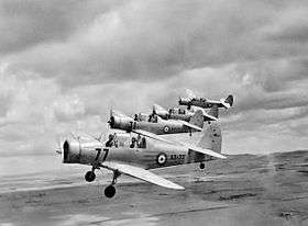 Three-quarter view of four military monoplanes in flight