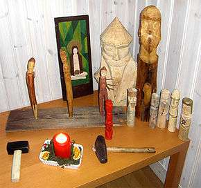 A wooden table indoors on which have been placed a number of wooden icons.