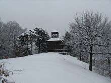 The brick building from the coin.  It is seen at a distance, and snow covers the ground.