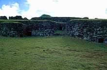 several windowless stone houses with grass roofs