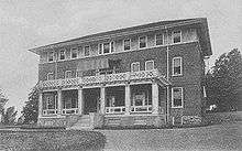 A three story brick building on a hill.