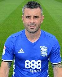 Grey-haired man wearing blue and white sports clothing