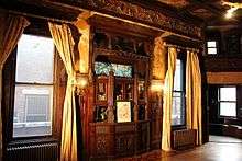 This is a photo of the Payne Mansion( Pi Kappa Phi Fraternity House) Dining room showing a Tiffany stained glass window, built in buffet, cherry inlaid floors and the choir loft.