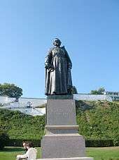 A gray steel statue of Père Jacques Marquette, atop a marble pedestal