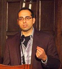 man standing at lectern reading