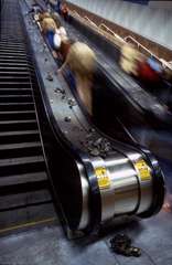 A set of escalators with bronzed gloves scatted in the area between the two.