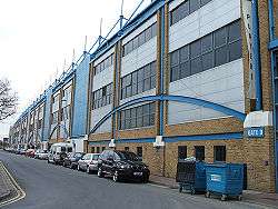 An external view of a sports stadium, with a large amount of blue detail on the facade.