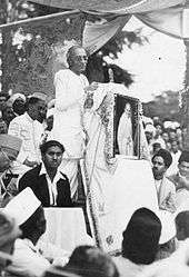 a person addressing a seated crowd