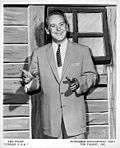 Red Foley standing in front of a window on a set