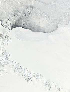 A wide expanse of ice covering the bottom two-thirds of the satellite image, and icy water covering the rest. There are dark mountains in the bottom-left.