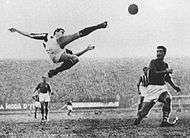 Photograph of a man who is about to strike a football in mid-air