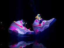 A pair of pink, neon sneakers on a black background