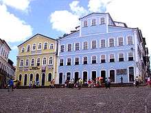 Large three-storied buildings with facades painted in bright colors: light blue and yellow.