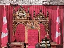 Three thrones with insignia flanked by two Canadian flags