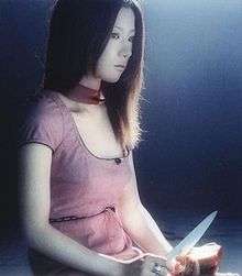 A woman stares off to her left, while cutting an apple in her hands.