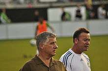 Two men with a player warming up behind them